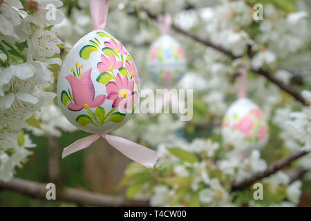 vintage Decorative Easter egg hanging on flowering cherry tree with white flowers. Easter banner background Stock Photo