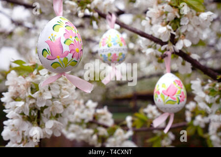 vintage Decorative Easter egg hanging on flowering cherry tree with white flowers. Easter banner background Stock Photo