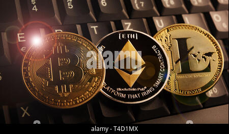 Bitcoin BTC, Ethereum ETH, Litecoin LTC coins on laptop keyboard Stock Photo