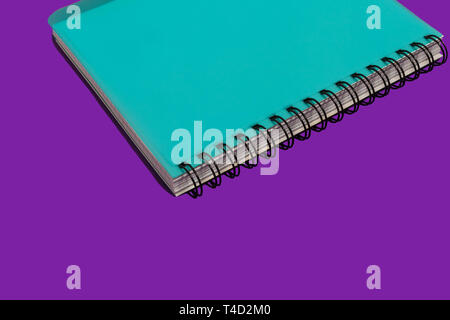 blue spiral notebook on a purple background Stock Photo