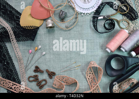 Sewing scene table flat lay composition. Threads, lace, pins, scissors, tape, reel, cloth. Pastel colors linen fabric text space. Top view banner Stock Photo