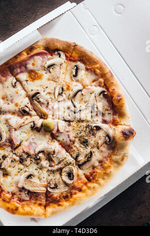 Cardboard box with delicious pizza on table Stock Photo