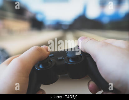 Man playing racing video game on TV. Gamepad controller in hands. Stock Photo