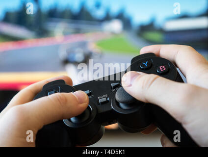 Man playing racing video game on TV. Gamepad controller in hands. Stock Photo