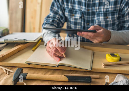 Carpenter using digital tablet to complete project to do list in small business woodwork workshop Stock Photo
