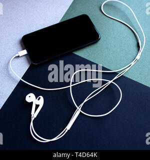 mobile phone with headphones in the shape of a violin key on the background of colored paper Stock Photo