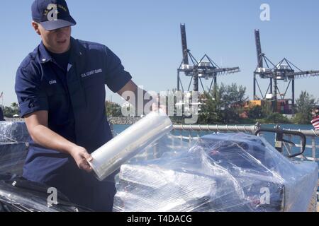 Coast Guard Petty Officer 3rd Class Mason R. Cram wraps a palette of cocaine in preparation for a drug offload Mar. 22, 2019 at Coast Guard Base Miami Beach. The crew of the Coast Guard Cutter Tampa offloaded approximately 27,000 pounds of cocaine worth an estimated $360 million wholesale seized in international waters in the Eastern Pacific Ocean. Coast Guard Stock Photo