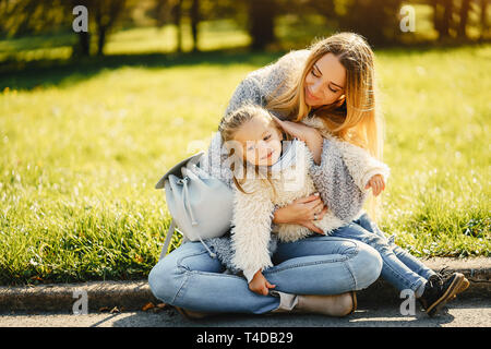 young mother with toddler daughter sitting on the groung hanging out and playing together in the park on a sunny day Stock Photo