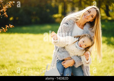 young mother with toddler daughter sitting on the groung hanging out and playing together in the park on a sunny day Stock Photo
