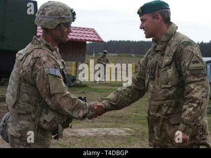 Brig. Gen. Leigh Tingey, the deputy commanding general for the 1st Armored Division out of Fort Bliss Texas, presents a coin to Capt. Kristopher Candelaria, the company commander for C Company, 1st Battalion, 35th Armored Regiment, 2nd Brigade Combat Team, 1st Armored Division, for his hard work during live-fire exercise in Drawsko Pomorskie Training Area, Poland, March 24.    At the direction of the Secretary of Defense, the 2nd Armored Brigade Combat Team, 1st Armored Division, deployed to Europe to exercise the U.S. Army's ability to rapidly alert, recall and deploy under emergency conditio Stock Photo