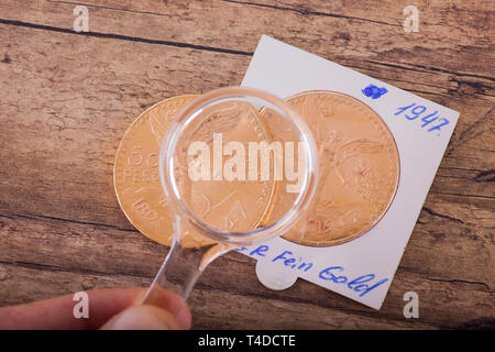 Two gold coins under magnifying glass Stock Photo