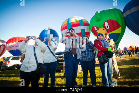 Onlookers at the Albuquerque International Hot Air Balloon Festival take pictures as the balloons take flight. Stock Photo