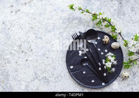 Easter table setting with white cherry blossom and cutlery on grey background. Mockup design layout for your text. Copy space. Top view. Flat lay. Stock Photo