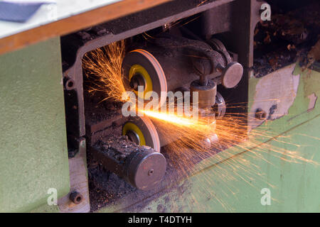 Mechanical stone for sharpening knives of split machines for leather. Sparks from grinding stone Stock Photo
