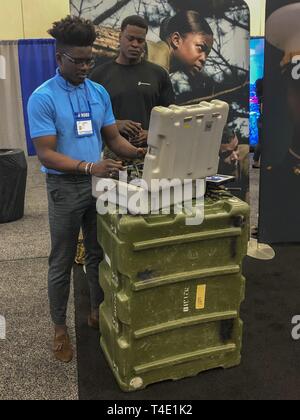 Maurice Diong, an engineer for Skanska, operates explosive ordnance disposal’s robot with Staff Sgt. Steven Bellamy, explosive ordnance disposal technician for 2nd EOD Company, 8th engineer support battalion, during a National Society of Black Engineers conference career fair in Detroit, Michigan, March 28. NSBE is holding its 45th annual national convention consisting of various programs and workshops that are designed to benefit grade school, collegiate, technical, professional and international attendees and the U.S. Marine Corps is a partner organization. Marines partner with organizations Stock Photo