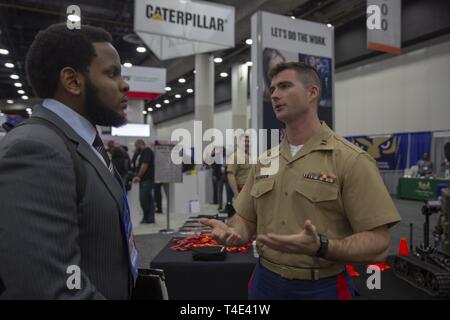 Marine Capt. James Butters, an officer selection officer from Ann Arbor Michigan, speaks with Michael McPherson from Embry-Riddle Aeronautical University, during a National Society of Black Engineers conference career fair in Detroit, Michigan, March 28, 2019. NSBE is holding its 45th annual national convention consisting of various programs and workshops that are designed to benefit grade school, collegiate, technical, professional and international attendees and the U.S. Marine Corps is a partner organization. Marines partner with organizations like NSBE to ensure its message of opportunity  Stock Photo