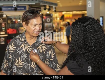 PEARL HARBOR (Mar. 29, 2019) Vietnam War veteran Stan Patalona is presented with a pin representing his recognizing his service by Porteia Falls from 'Guaranteed Rate,' who helped sponsor the event. On March 28, 2017, President Donald J. Trump signed into law the Vietnam War Veterans Recognition Act, designated every March 29 as National Vietnam War Veterans Day. Stock Photo