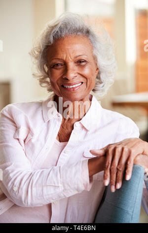 Portrait Of Smiling Senior Woman Relaxing On Sofa At Home Stock Photo