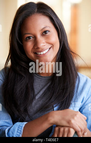 Portrait Of Smiling Woman Relaxing On Sofa At Home Stock Photo