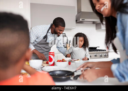 Family In Kitchen At Home Making Pancakes Together Stock Photo