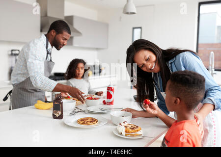 Family In Kitchen At Home Making Pancakes Together Stock Photo