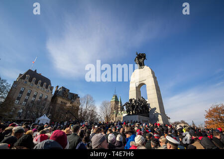 OTTAWA, CANADA - NOVEMBER 11, 2018: Crowd gathering on National War memorial, with parliament in background, on remembrance day to commemorate the can Stock Photo