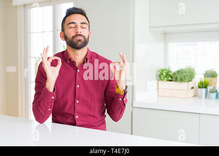 Handsome hispanic business man relax and smiling with eyes closed doing meditation gesture with fingers. Yoga concept. Stock Photo
