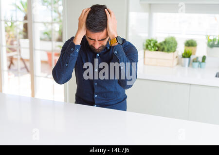 Handsome hispanic man suffering from headache desperate and stressed because pain and migraine. Hands on head. Stock Photo