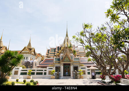 BANGKOK, THAILAND - MARCH 2019: View over Grand Palace and Chakri Maha Prasat hall through the trees and bushes at sunny day