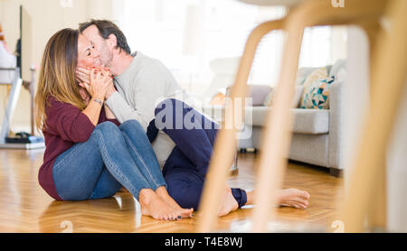 Beautiful romantic couple sitting together on the floor kissing in love at home Stock Photo