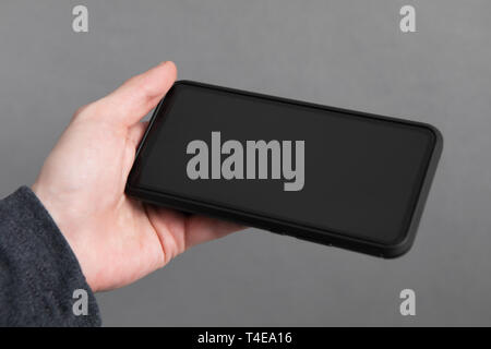 Mans hand holding black screen mobile phone Stock Photo