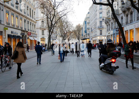 People, tourists, office workers walking and riding along Rue de la République pedestrian mall in the Cordeliers neighborhood of Lyon, France (2019) Stock Photo