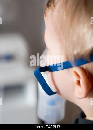 Small child inhaling with oxygen mask side view close up Stock Photo