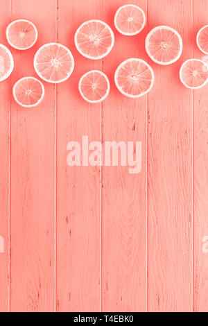 Creative scandinavian style flat lay top view of fresh orange fruit slices on coral wooden table background with copy space. Minimal summer fresh citr Stock Photo