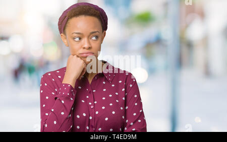 Beautiful young african american woman wearing head scarf over isolated background thinking looking tired and bored with depression problems with cros Stock Photo