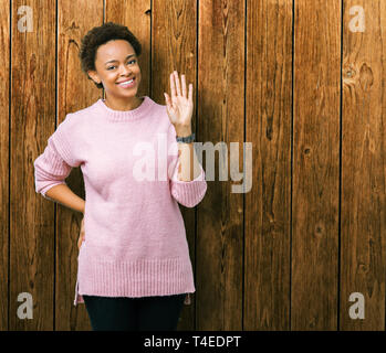 Beautiful young african american woman over isolated background Waiving saying hello happy and smiling, friendly welcome gesture Stock Photo