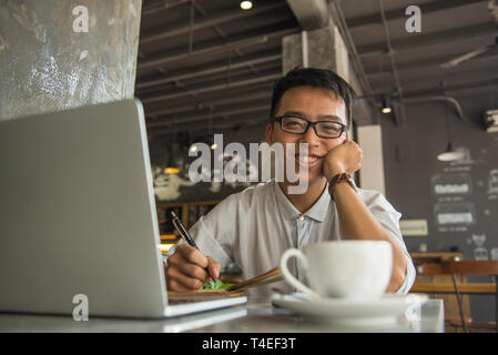 Asian freelancer smiling and working in the cafe Stock Photo