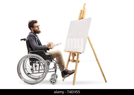 Disabled male artist in a wheelchair painting on a canvas isolated on white background Stock Photo