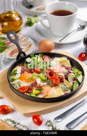 Sunny side up eggs with crispy fried bacon, fresh lettuce and tomatoes in fry pan Stock Photo