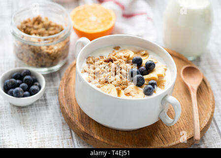Healthy breakfast cereals granola with milk and fruits in a bowl on wooden table background. Closeup view, selective focus Stock Photo