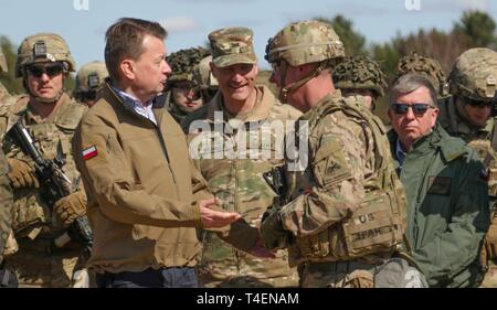 Mariusz Blaszczak, the Polish Minister of National Defense, shares a laugh with Col. Patrick Michaelis, commander of the Mission Command Element in Poznan, Poland, and Col. Chad Chalfont, commander of the 2nd Armored Brigade Combat Team, 1st Armored Division out of Fort Bliss, Texas, during a joint demonstration in the Drawsko Pomorskie Training Area in Drawsko Pomorskie, Poland, April 1.     At the direction of the Secretary of Defense, the 2nd Armored Brigade Combat Team, 1st Armored Division, deployed to Europe to exercise the U.S. Army's ability to rapidly alert, recall and deploy under em Stock Photo