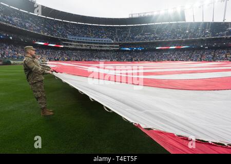 More than 100 servicemembers from Whiteman Air Force Base, Missouri unfurl the American Flag during the national anthem on March 28, 2019, at Kauffman Stadium, Kansas City, Missouri. During the opening game service members and veterans of all five branches of the military were recognized. Stock Photo