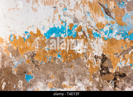 wall of plaster white yellow blue peeling paint. Cement grunge background Stock Photo