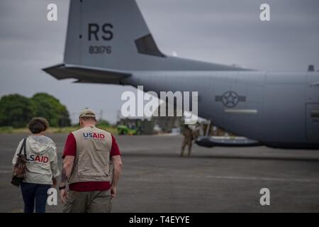 U.S. Agency for International Development (USAID) workers walk toward a C-130J Hercules assigned to the 75th Expeditionary Airlift Squadron, Combined Joint Task Force-Horn of Africa, at the airport in Maputo, Mozambique, April 5, 2019. The task force is helping meet requirements identified by USAID assessment teams and humanitarian organizations working in the region by providing logistics support and manpower to USAID at the request of the Government of the Republic of Mozambique. Stock Photo