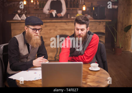 Successful businessmen having a meeting about finances and industry in a coffee shop. Young entrepreneurs. Stock Photo