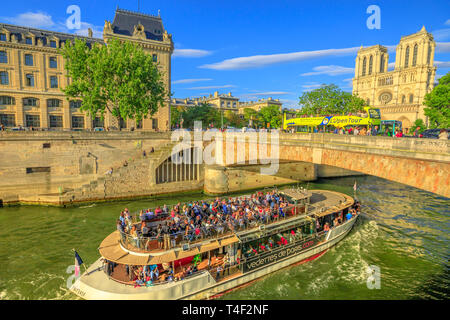 Paris, France - July 1, 2017: Bateaux-Mouches with many tourist during a trip at sunset on River Seine with Cathedral of Notre Dame on the Ile de la Stock Photo