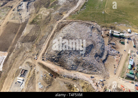 Aerial top drone view of large garbage pile, trash dump, landfill, waste from household dumping site, excavator machine is working on a mountain of ga Stock Photo