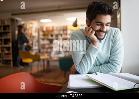 Happy student preparing exam and learning lessons in college library Stock Photo