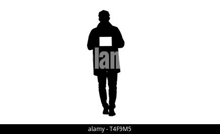 Silhouette Young man walking, talking and showing digital tablet with white screen mockup. Stock Photo