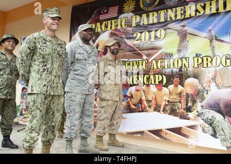 Malaysia (April 11, 2019) – Malaysian Army along with U.S. Navy Seabees, U.S. Air Force, and the Royal Canadian Medical Service celebrate the end of an enclosure project during a ribbon cutting ceremony at Sambir Elementary School. These engagements promote cooperation and friendship between Pacific Partnership 2019 participants and the host nation. Pacific Partnership, now in its 14th iteration, is the largest annual multinational humanitarian assistance and disaster relief preparedness mission conducted in the Indo-Pacific. Each year the mission team works collectively with host and partner  Stock Photo